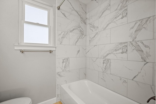 bathroom with plenty of natural light, tiled shower / bath combo, and toilet