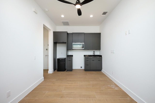 kitchen with light wood-type flooring, ceiling fan, and sink