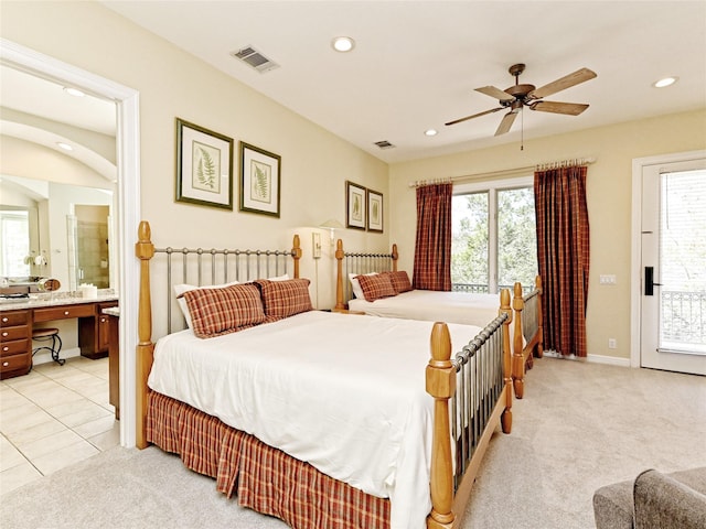 bedroom with ensuite bath, light colored carpet, and ceiling fan