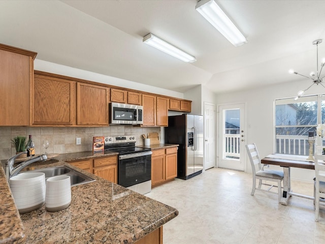 kitchen featuring pendant lighting, a notable chandelier, backsplash, appliances with stainless steel finishes, and sink