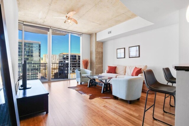 living room with a wall of windows, ceiling fan, hardwood / wood-style flooring, and a healthy amount of sunlight