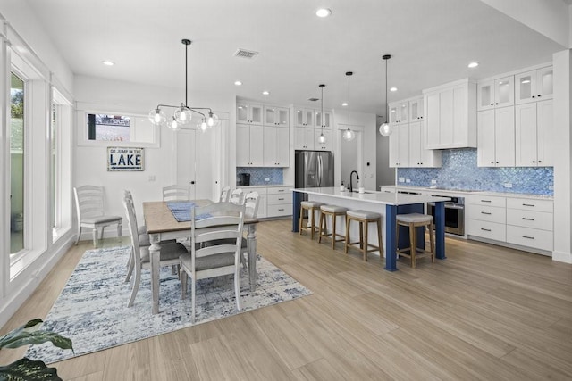 dining space with light hardwood / wood-style floors, a notable chandelier, and sink