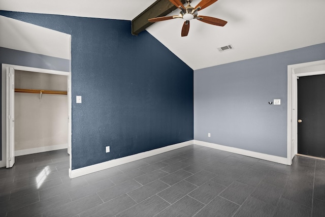 unfurnished bedroom with dark tile patterned flooring, a closet, ceiling fan, and vaulted ceiling with beams