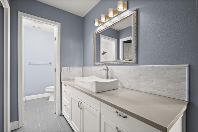 bathroom with backsplash, vanity, and toilet