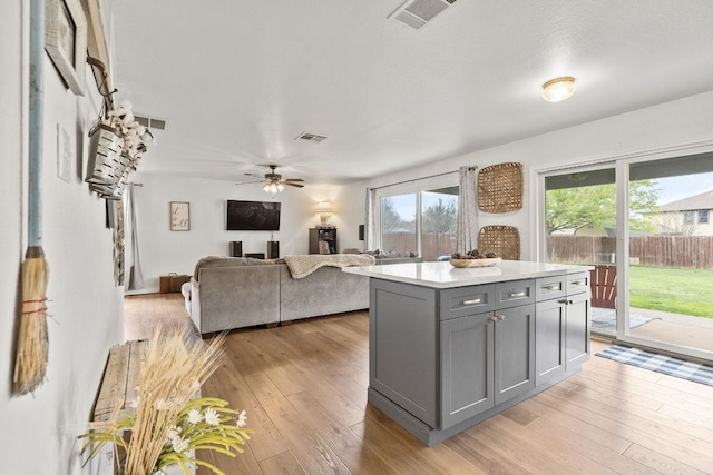 kitchen with ceiling fan, a center island, light hardwood / wood-style flooring, and gray cabinetry