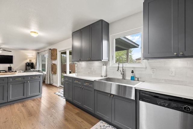 kitchen featuring sink, dishwasher, gray cabinetry, backsplash, and light hardwood / wood-style floors