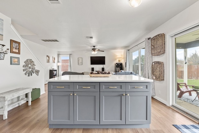 kitchen featuring a healthy amount of sunlight, gray cabinetry, and light wood-type flooring