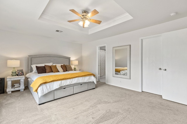 carpeted bedroom featuring ceiling fan, ornamental molding, and a tray ceiling