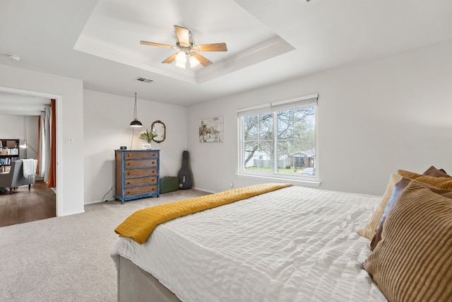 bedroom with crown molding, ceiling fan, a raised ceiling, and carpet