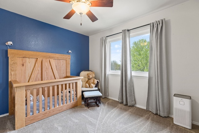 bedroom with a crib, carpet flooring, and ceiling fan