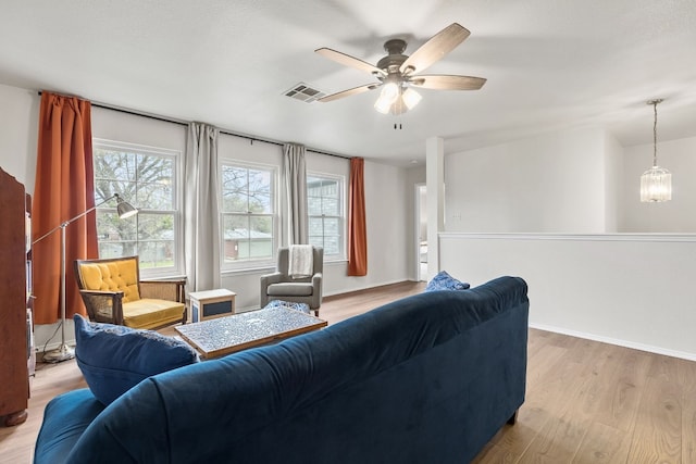 living room featuring ceiling fan with notable chandelier, light hardwood / wood-style flooring, and a wealth of natural light