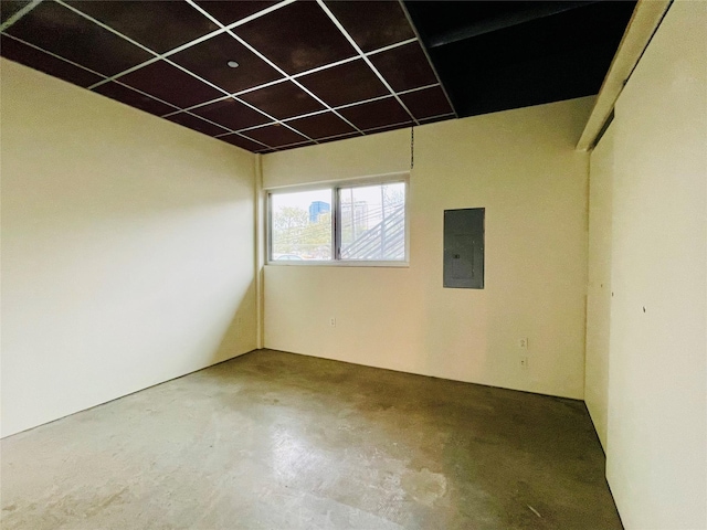 spare room featuring electric panel, concrete floors, and a paneled ceiling