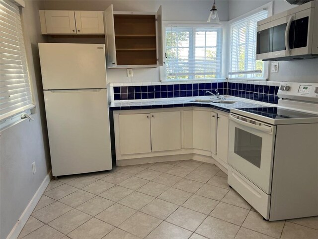 kitchen with white appliances, white cabinetry, and tile counters