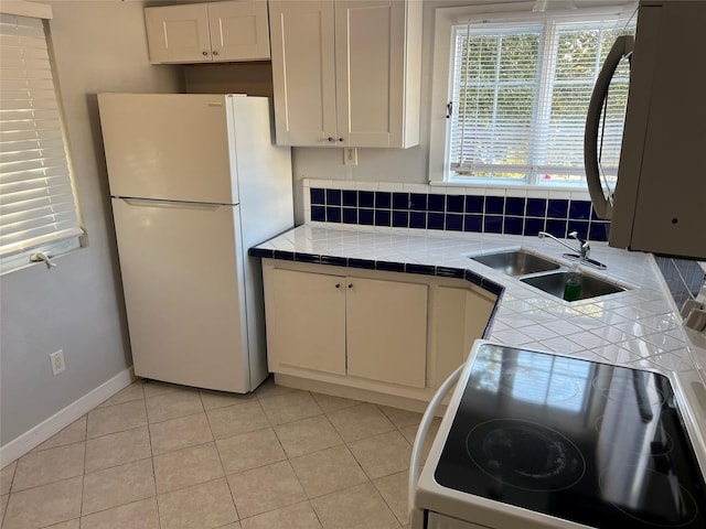 kitchen featuring white appliances, tile counters, light tile patterned floors, white cabinetry, and sink