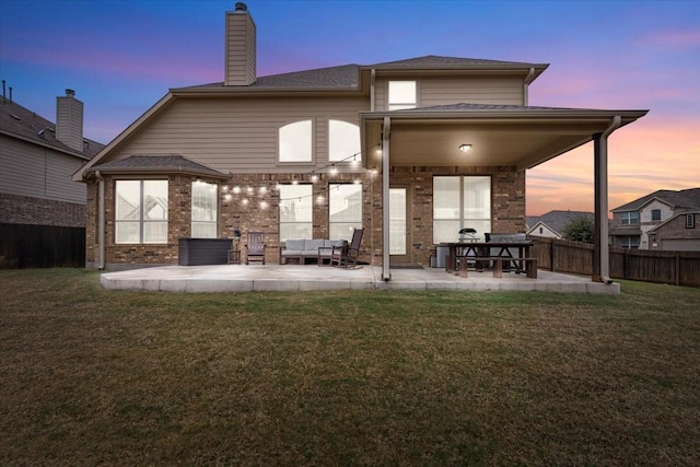 back house at dusk with a yard, outdoor lounge area, and a patio area