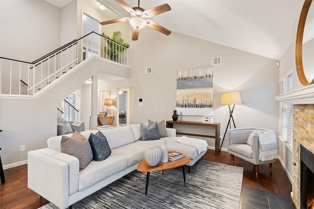 living room with high vaulted ceiling, ceiling fan, dark wood-type flooring, and a tile fireplace