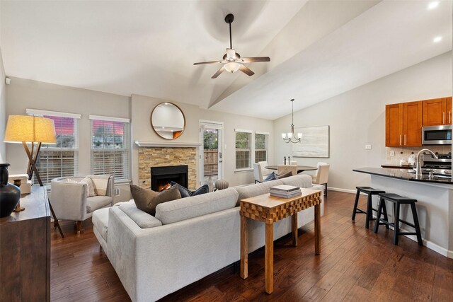 living room featuring lofted ceiling, a fireplace, ceiling fan with notable chandelier, and dark hardwood / wood-style floors