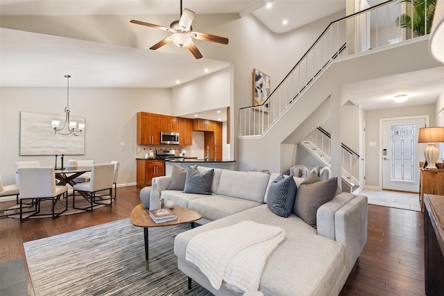 living room with high vaulted ceiling, dark wood-type flooring, and ceiling fan with notable chandelier