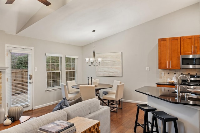 dining area with lofted ceiling, dark hardwood / wood-style floors, sink, and ceiling fan with notable chandelier