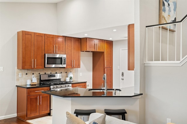 kitchen featuring a kitchen bar, kitchen peninsula, stainless steel appliances, a towering ceiling, and sink