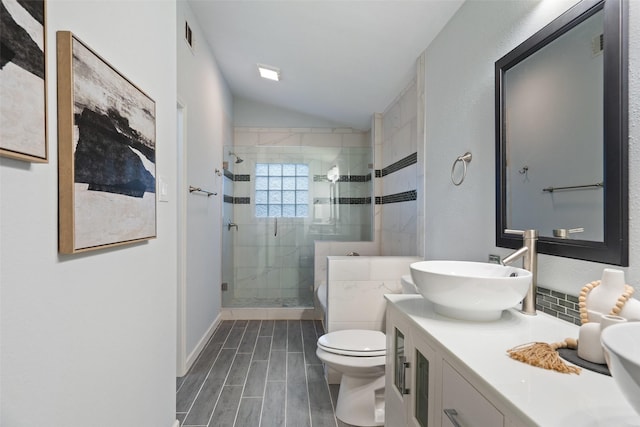 bathroom featuring toilet, vaulted ceiling, a shower with door, and vanity