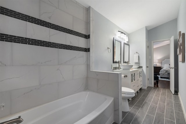 bathroom featuring toilet, a tub to relax in, and vanity