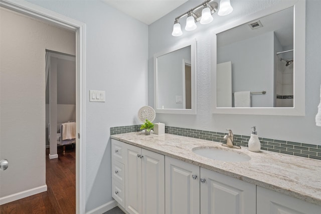 bathroom with vanity, backsplash, and hardwood / wood-style floors