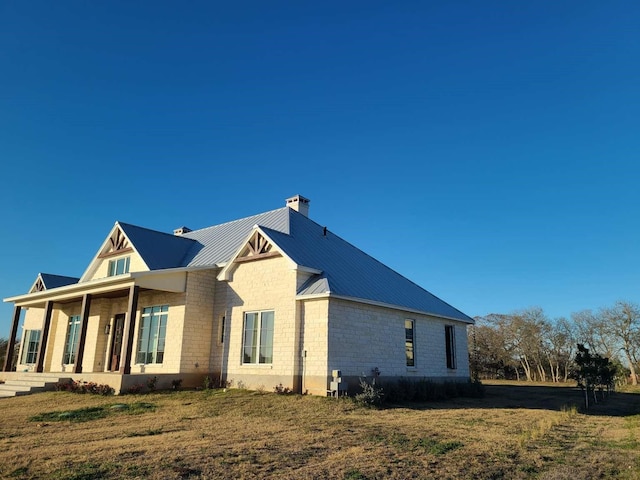 view of side of property with covered porch and a yard