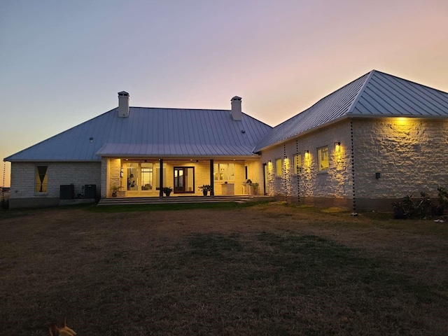 back house at dusk featuring central AC and a yard