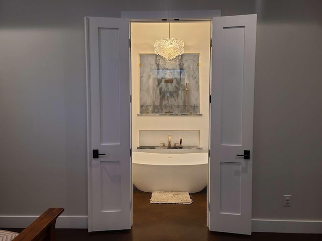 bathroom with a washtub and a chandelier