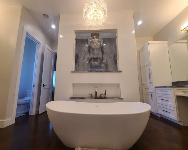 bathroom with vanity, an inviting chandelier, a tub, toilet, and hardwood / wood-style flooring