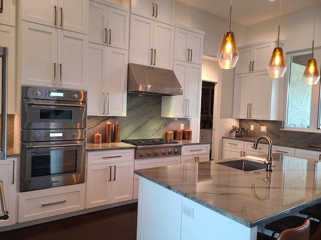 kitchen with backsplash, pendant lighting, sink, stainless steel appliances, and white cabinets