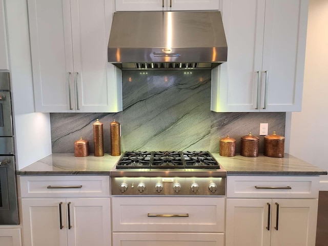 kitchen with white cabinetry, appliances with stainless steel finishes, tasteful backsplash, and range hood