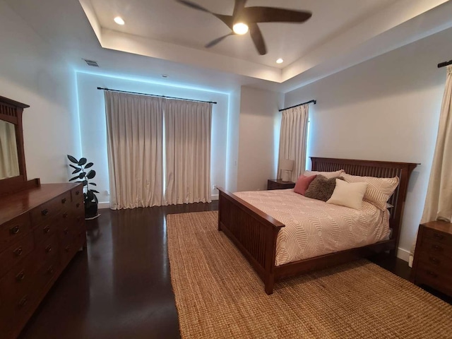 bedroom featuring ceiling fan, wood-type flooring, and a tray ceiling