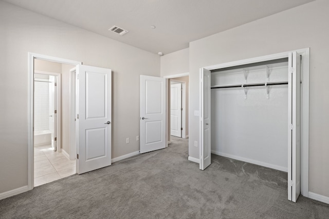 unfurnished bedroom with light colored carpet and a closet