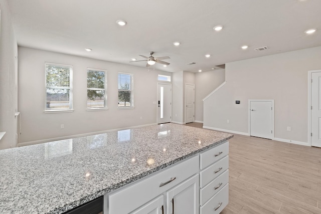 kitchen with light stone counters, ceiling fan, light hardwood / wood-style floors, and white cabinetry