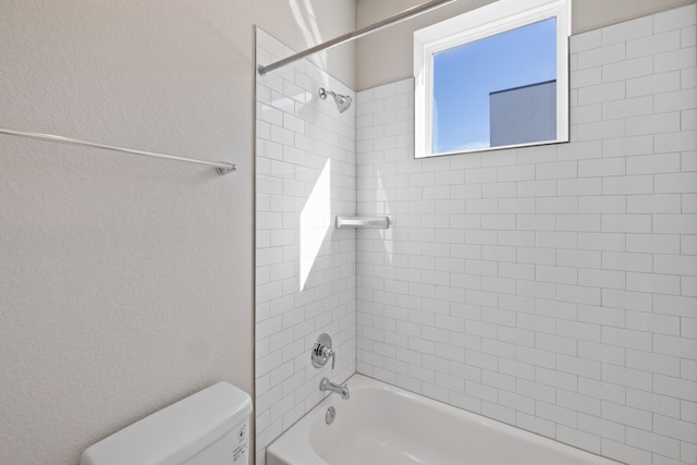 bathroom with toilet and tiled shower / bath combo