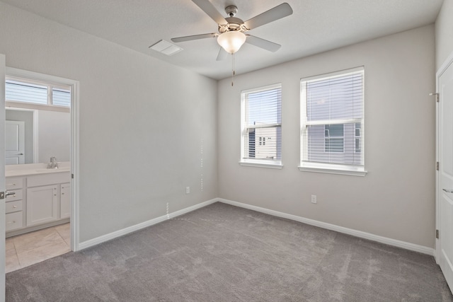 unfurnished bedroom featuring sink, connected bathroom, ceiling fan, and light colored carpet