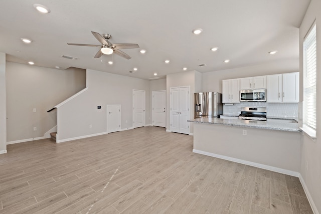 kitchen with stainless steel appliances, white cabinetry, ceiling fan, light hardwood / wood-style flooring, and light stone countertops