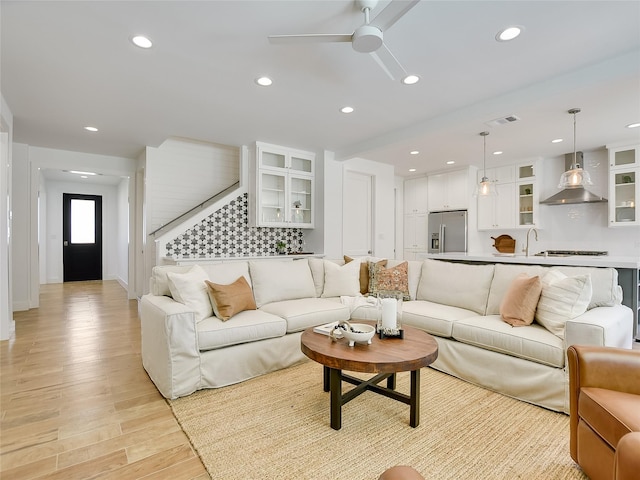 living room with ceiling fan, light wood-type flooring, and sink