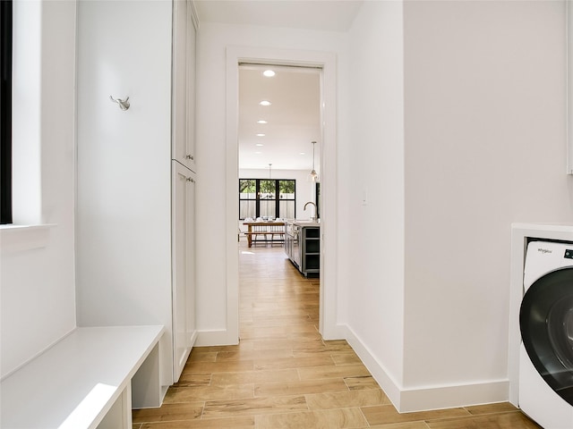 washroom featuring sink, cabinets, light hardwood / wood-style flooring, washer / dryer, and a notable chandelier