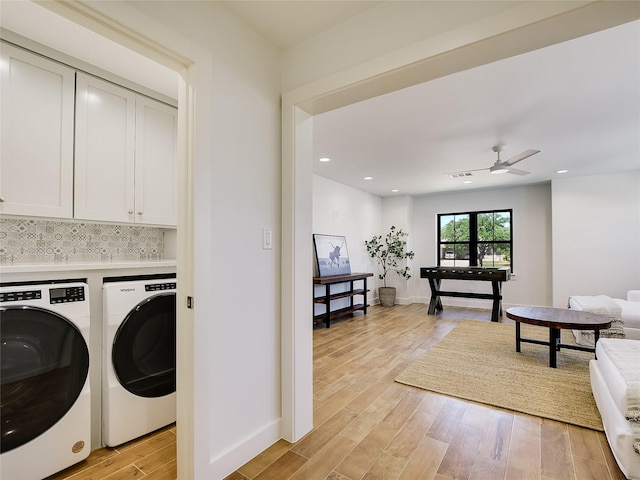 laundry area with washing machine and clothes dryer, ceiling fan, light hardwood / wood-style floors, and cabinets