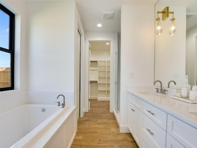 bathroom with vanity, hardwood / wood-style floors, and a relaxing tiled tub