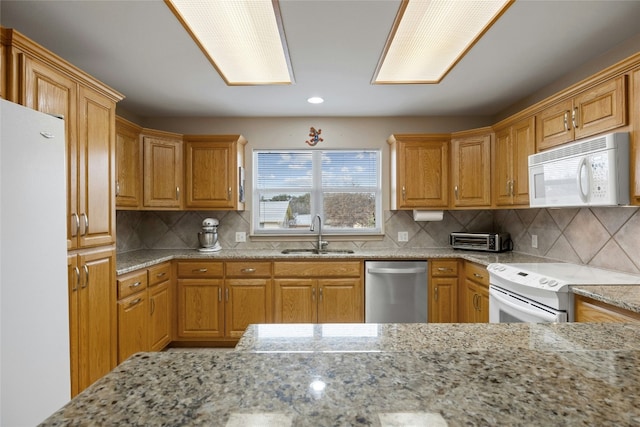 1505 E Johnson St, Burnet, TX 78611 - kitchen with white appliances, light stone countertops, backsplash, recessed lighting, and brown cabinets
