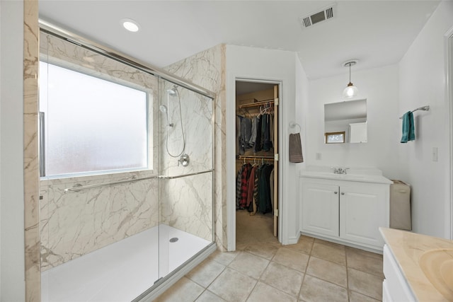 bathroom featuring tile patterned floors, vanity, and a tile shower