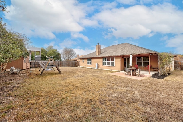1505 E Johnson St, Burnet, TX 78611 - rear view of property featuring a fenced backyard, a playground, a patio area, and a chimney