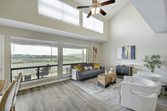 living room with ceiling fan, high vaulted ceiling, plenty of natural light, and wood-type flooring