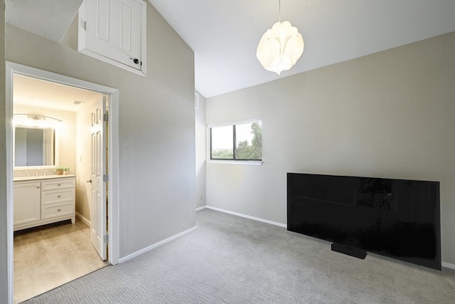 interior space featuring lofted ceiling, ensuite bath, and light carpet