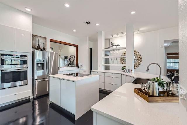 kitchen featuring stainless steel appliances, sink, a center island, white cabinetry, and kitchen peninsula