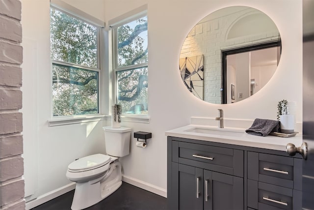 bathroom with toilet, vanity, and a healthy amount of sunlight